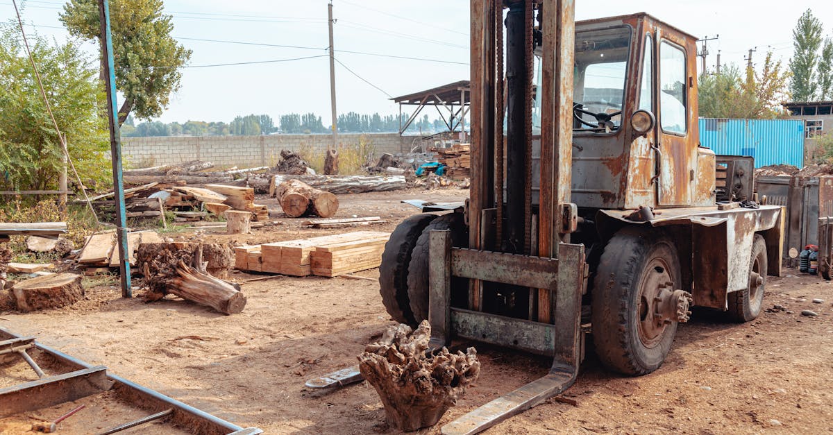 Old forklift in a rustic sawmill setting, surrounded by logs and lumber, hinting at heavy industry.